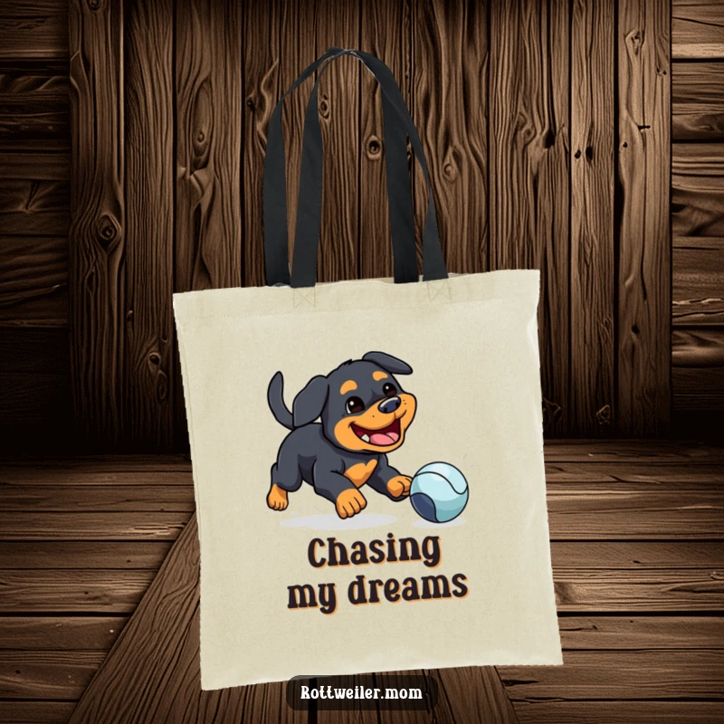 Funny tote bag featuring a kawaii Rottweiler with a silly grin, chasing a bouncing ball, ideal for carrying groceries with humor.